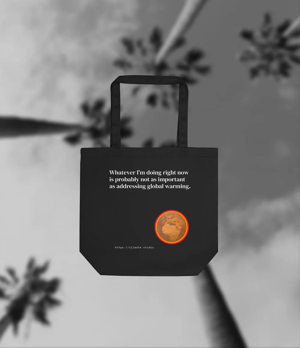 Black tote bag with climate message against beach background