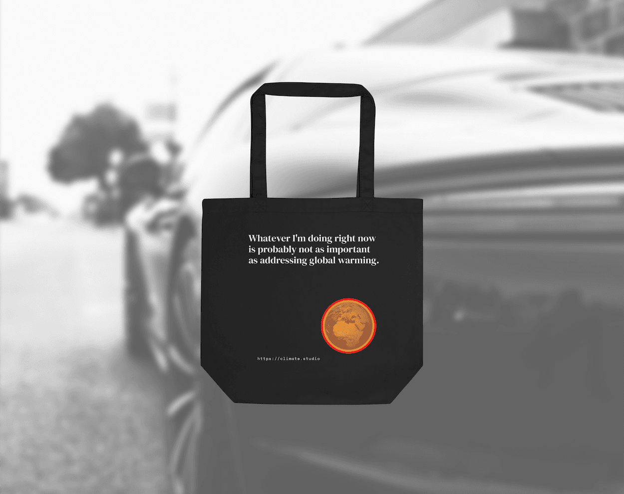 Black tote bag with climate message against car background